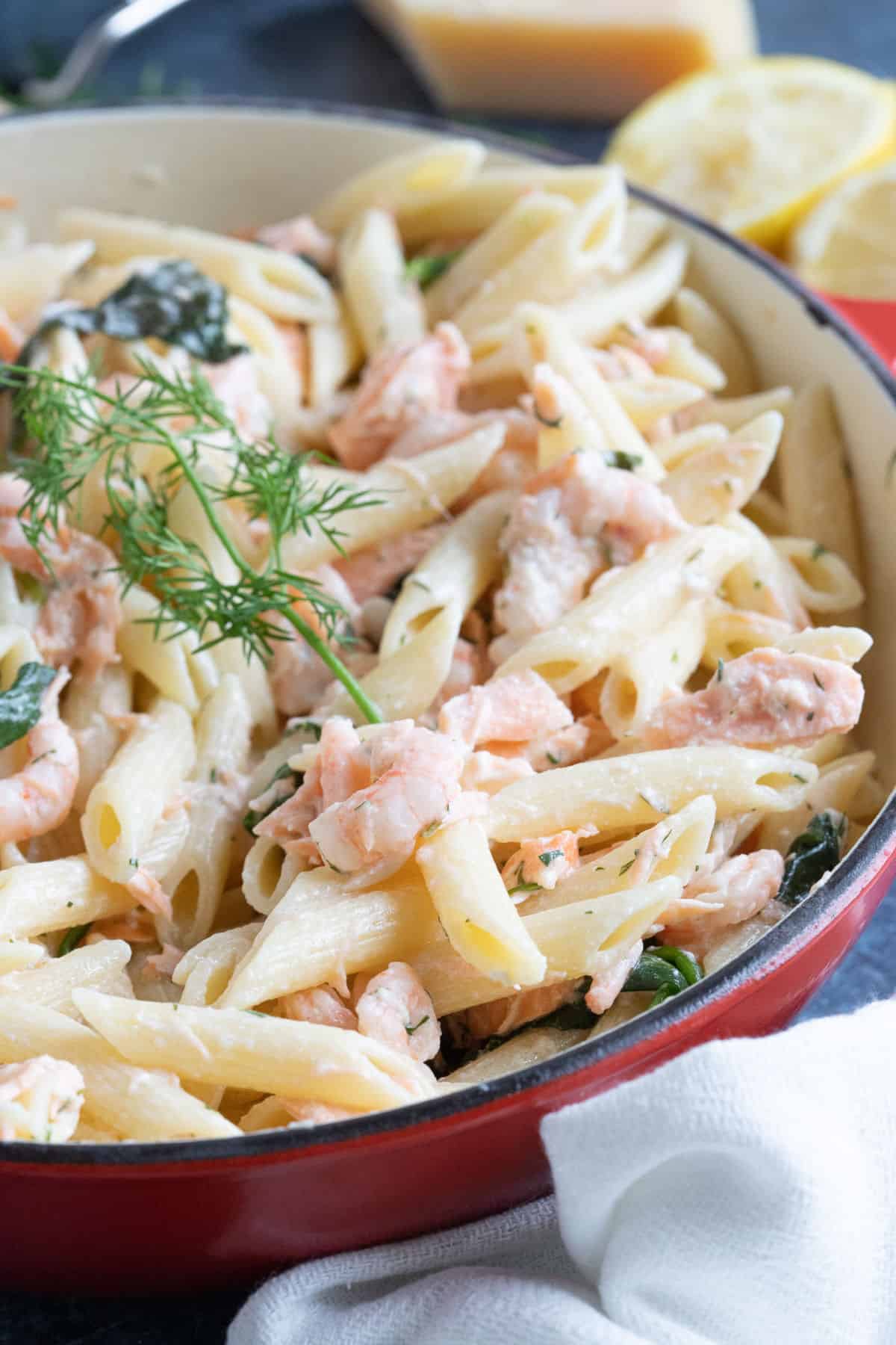 Salmon and prawn pasta in a red pan.