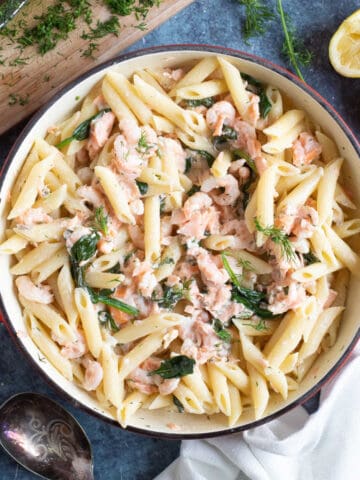 Salmon and prawn pasta with chopped dill on top.