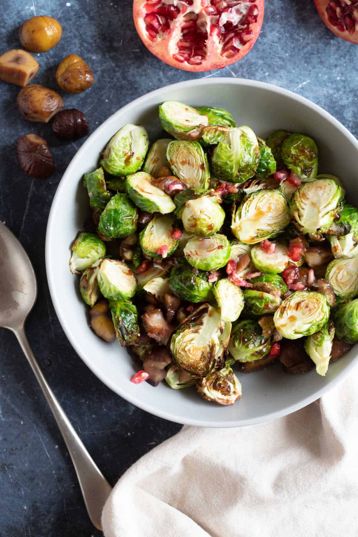 Air fryer Brussles sprouts in a grey bowl with pomegranate seeds.