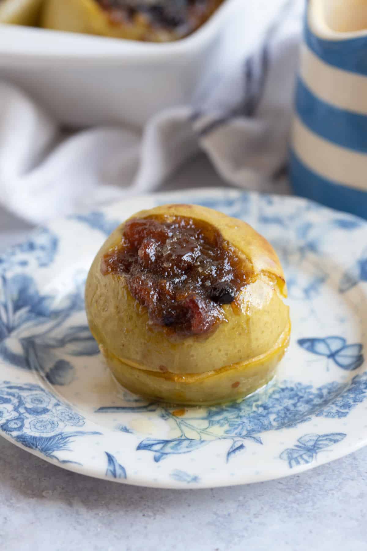 A baked apple with mincemeat on a dessert plate.