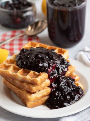 Blackcurrant compote spooned over waffles.