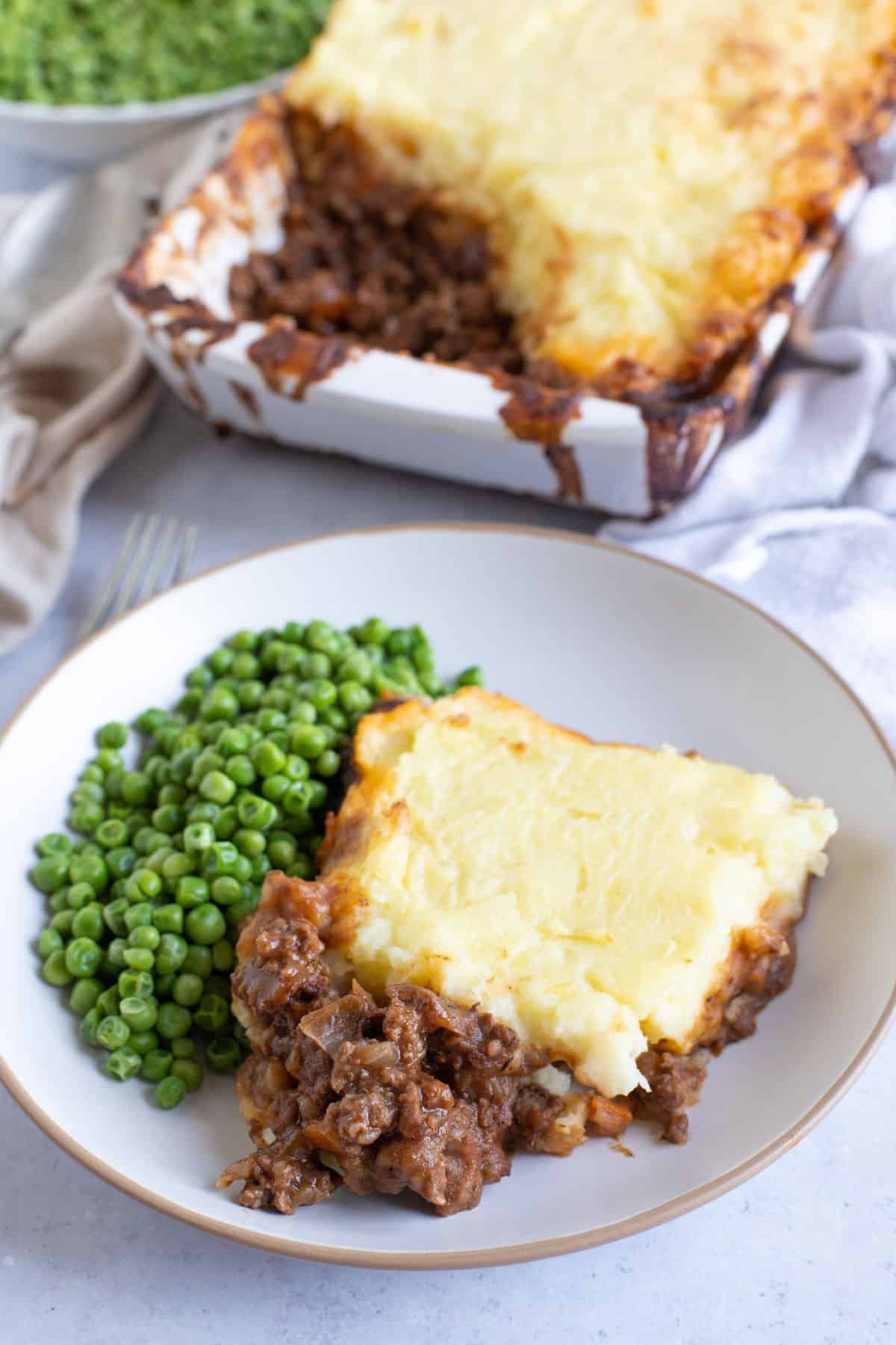 A plate of cottage pie and peas.