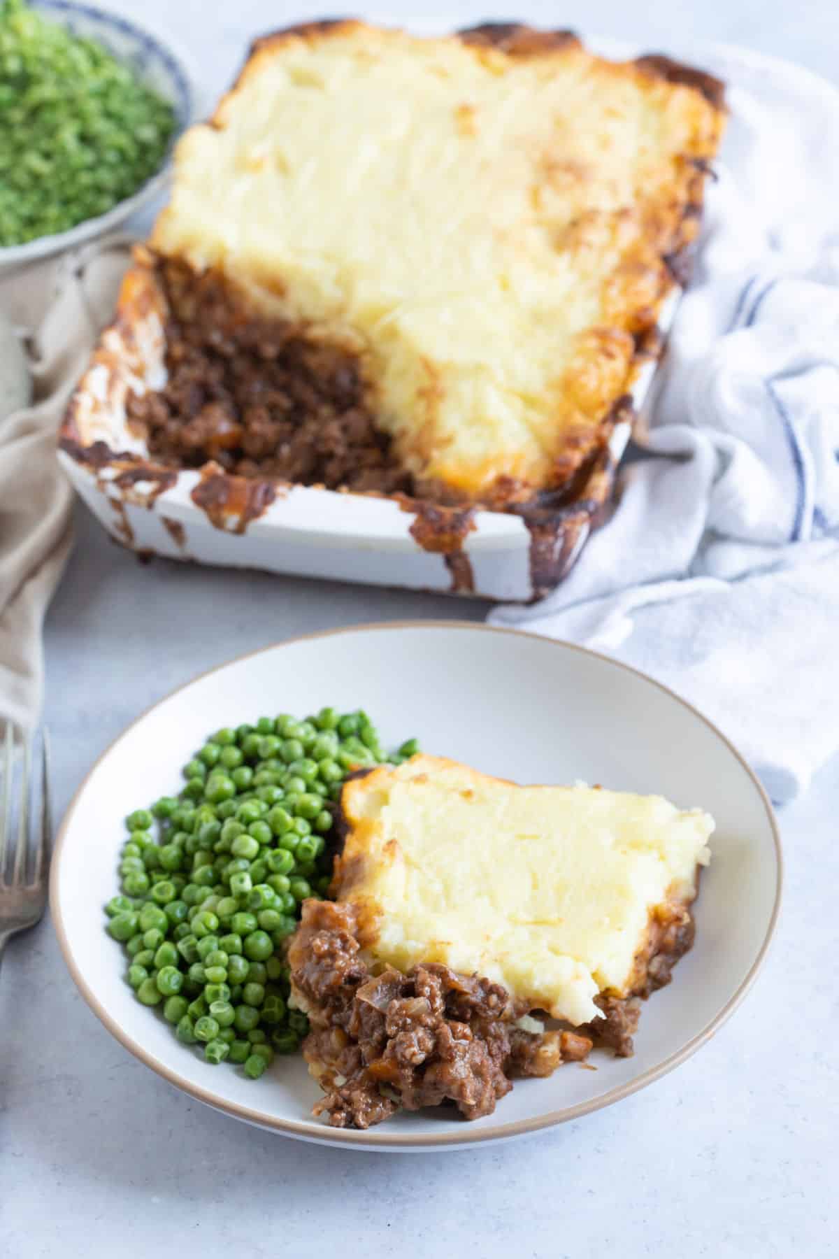 A plate of cottage pie and peas.