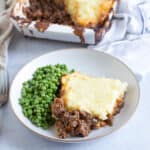 Cottage pie on a plate with peas.