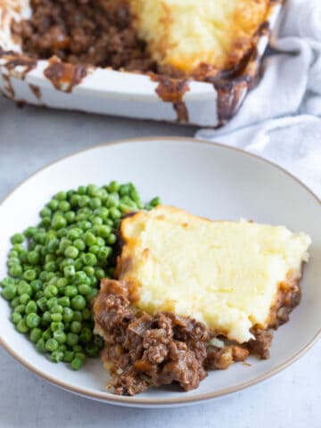 Cottage pie on a plate with peas.