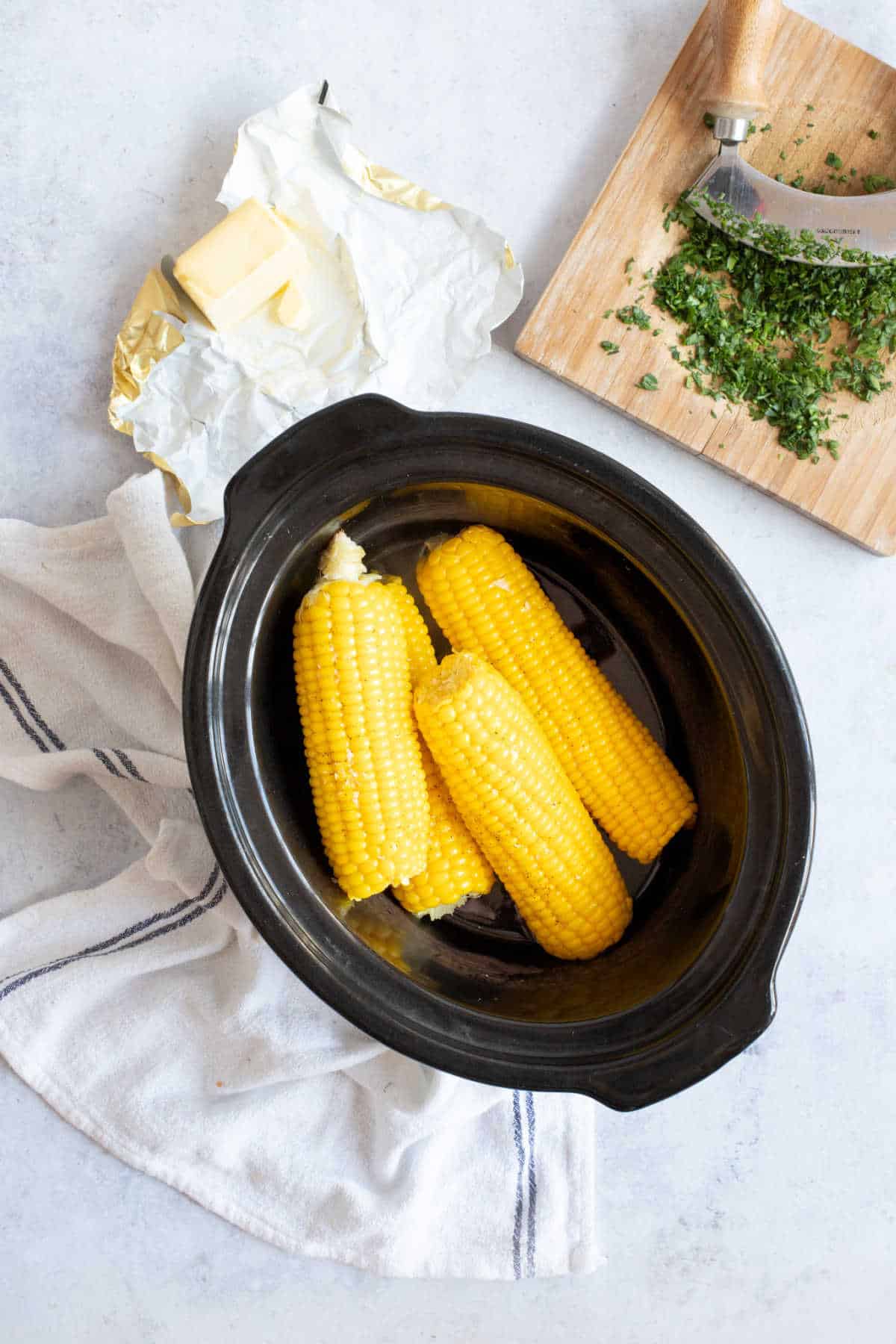 Corn on the cob in the slow cooker with bitter and parsley.