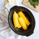 Corn on the cob in a slow cooker basin.