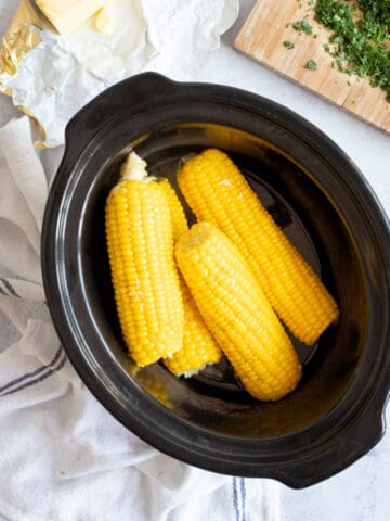 Corn on the cob in a slow cooker basin.