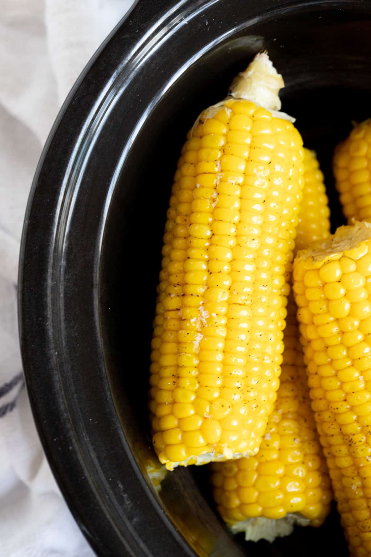 Corn in a black slow cooker.