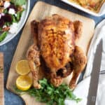 Slow cooker whole chicken on a wooden board.