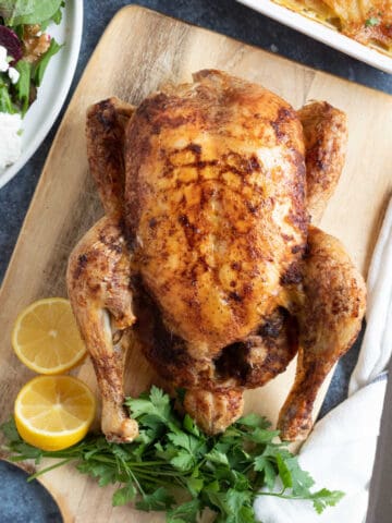 Slow cooker whole chicken on a wooden board.