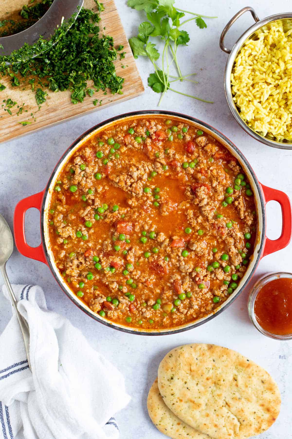 Turkey keema curry in a red pan with pilau rice and coriander.