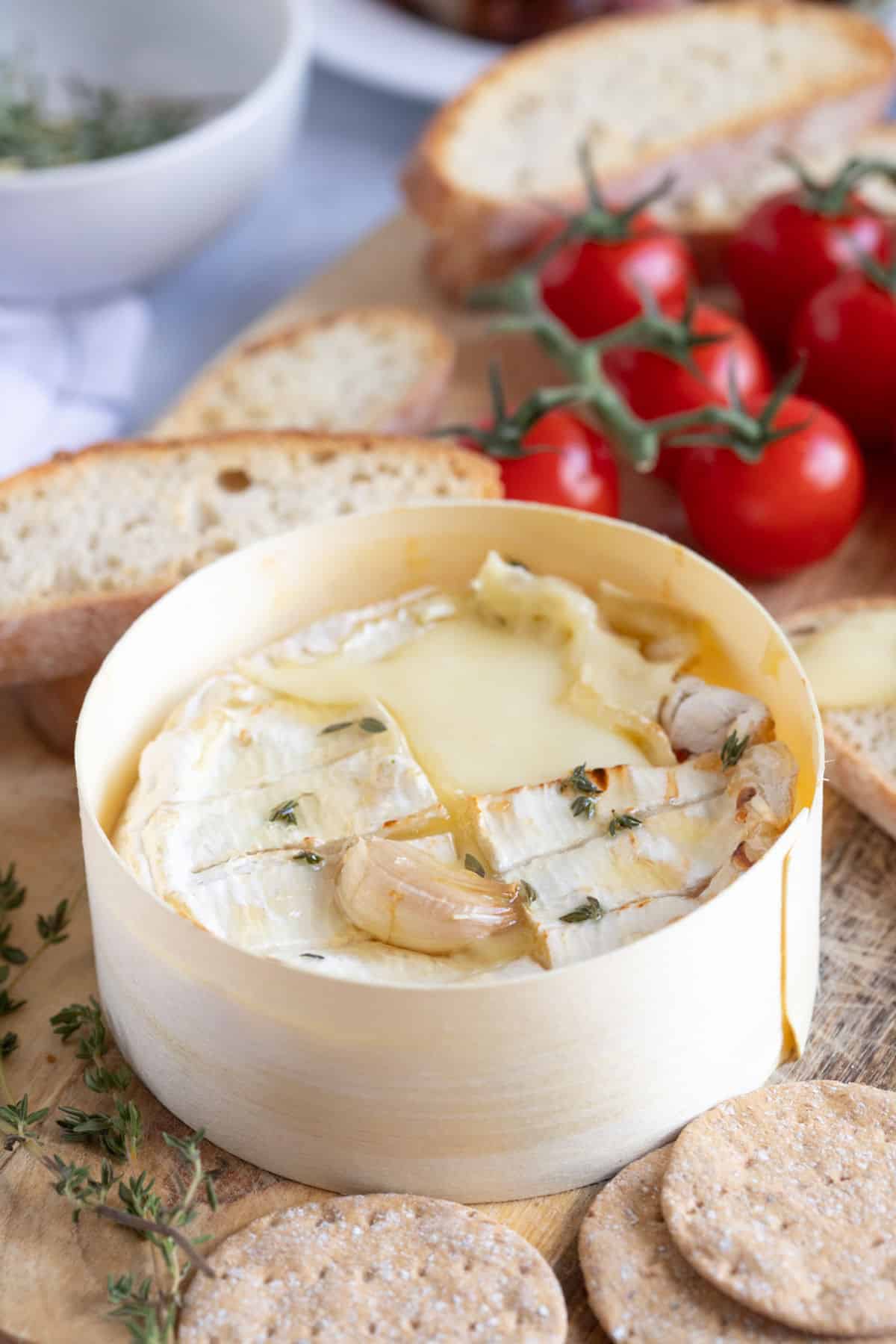 A baked camembert on a wooden serving board.