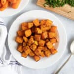 Air fryer butternut squash cubes on a white plate.