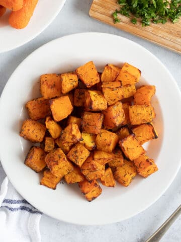 Air fryer butternut squash cubes on a white plate.