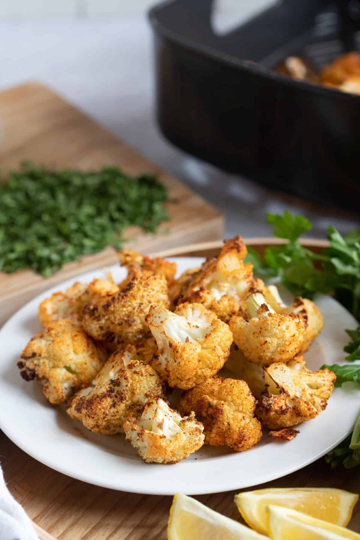 Roasted cauliflower with an air fryer basket behind.