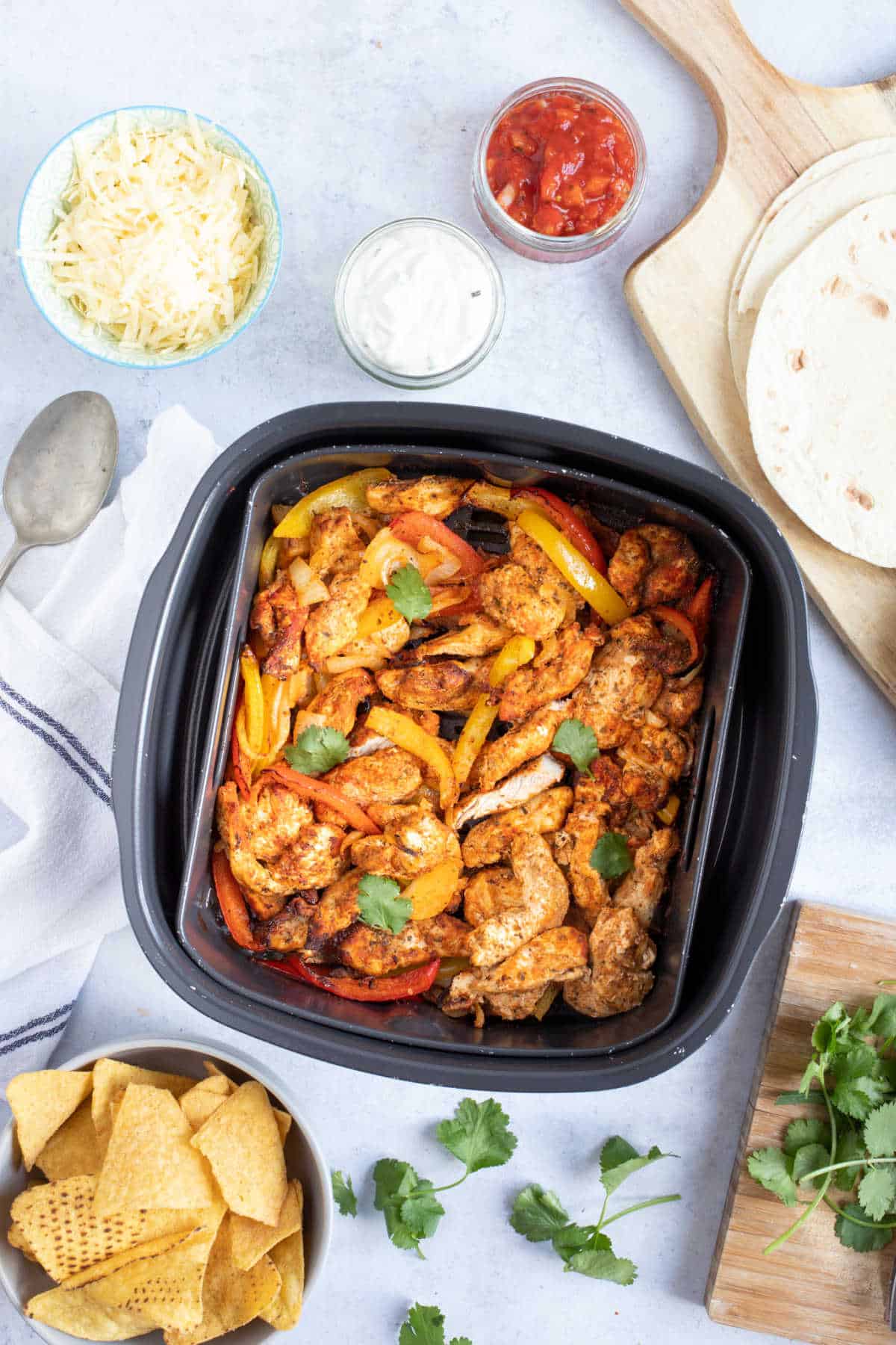 Chicken fajitas in an air fryer basket.