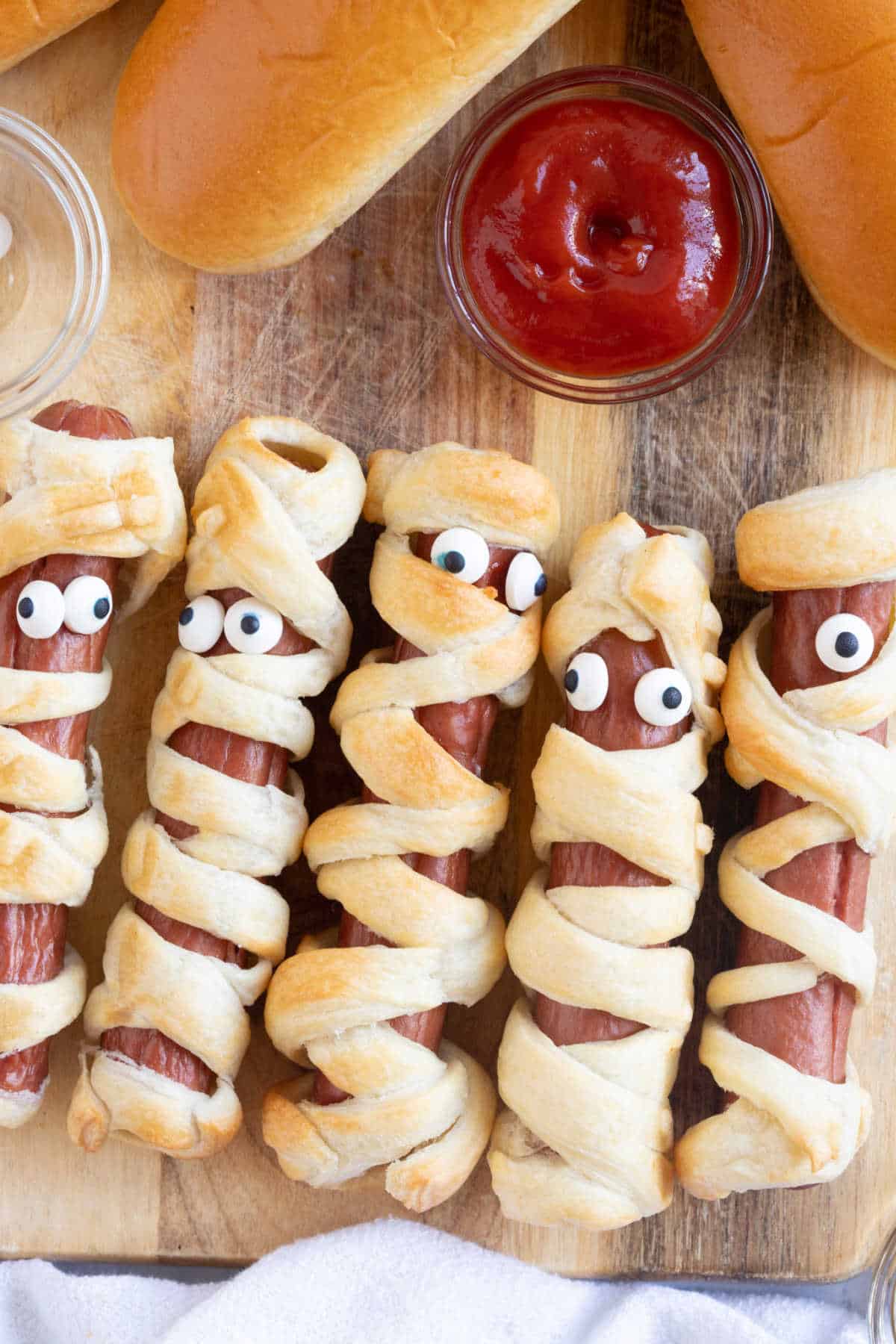 Air fryer mummy hot dogs on a wooden board.