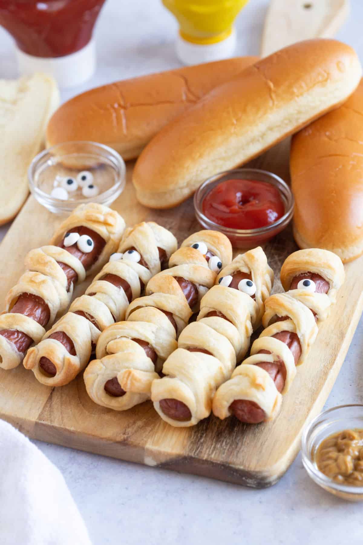 Halloween mummy dogs on a wooden board.