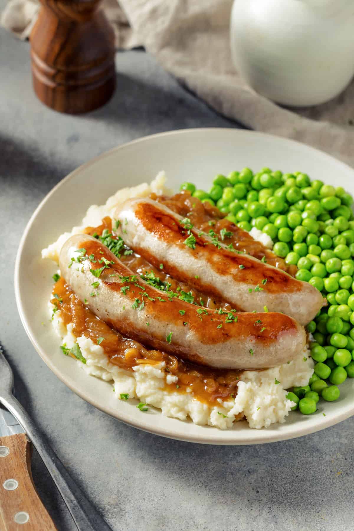 Air fryer sausages, mash and peas o a plate.