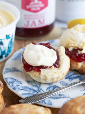 Air fryer scone on a blue plate with jam and clotted cream.