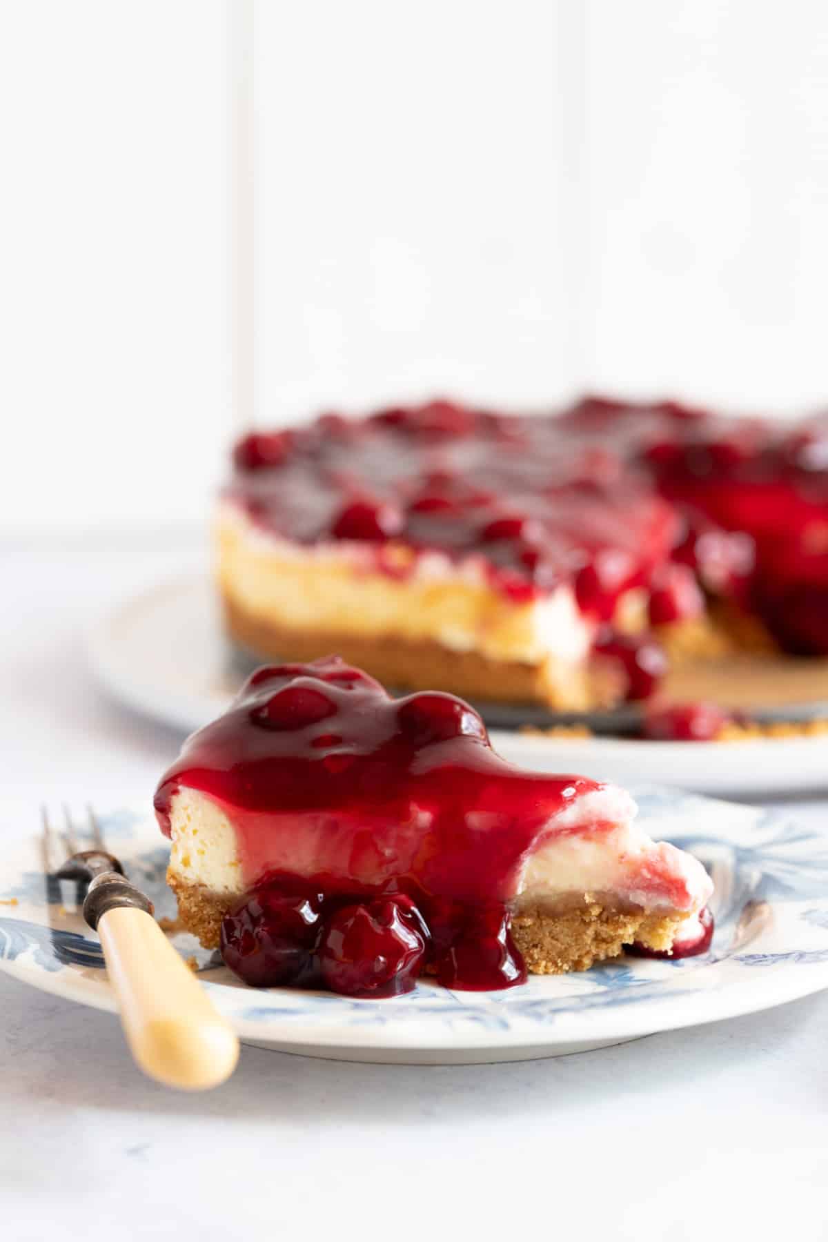 A slice of cherry cheesecake on a dessert plate.