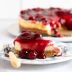 A slice of cherry cheesecake on a blue and white plate.