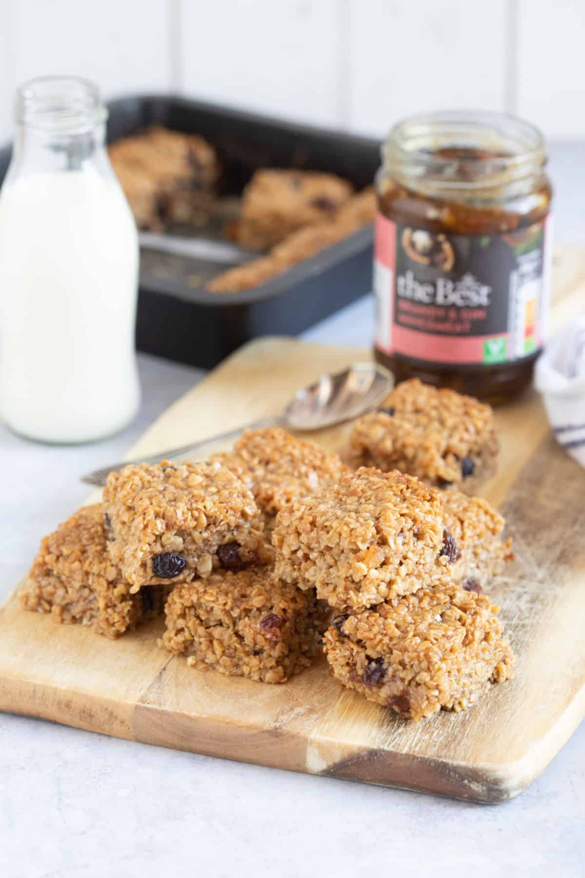 Mincemeat flapjacks on a wooden board with a jar of mincemeat behind.