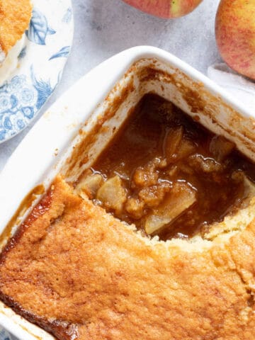 Sticky toffee apple pudding in a white pie dish.