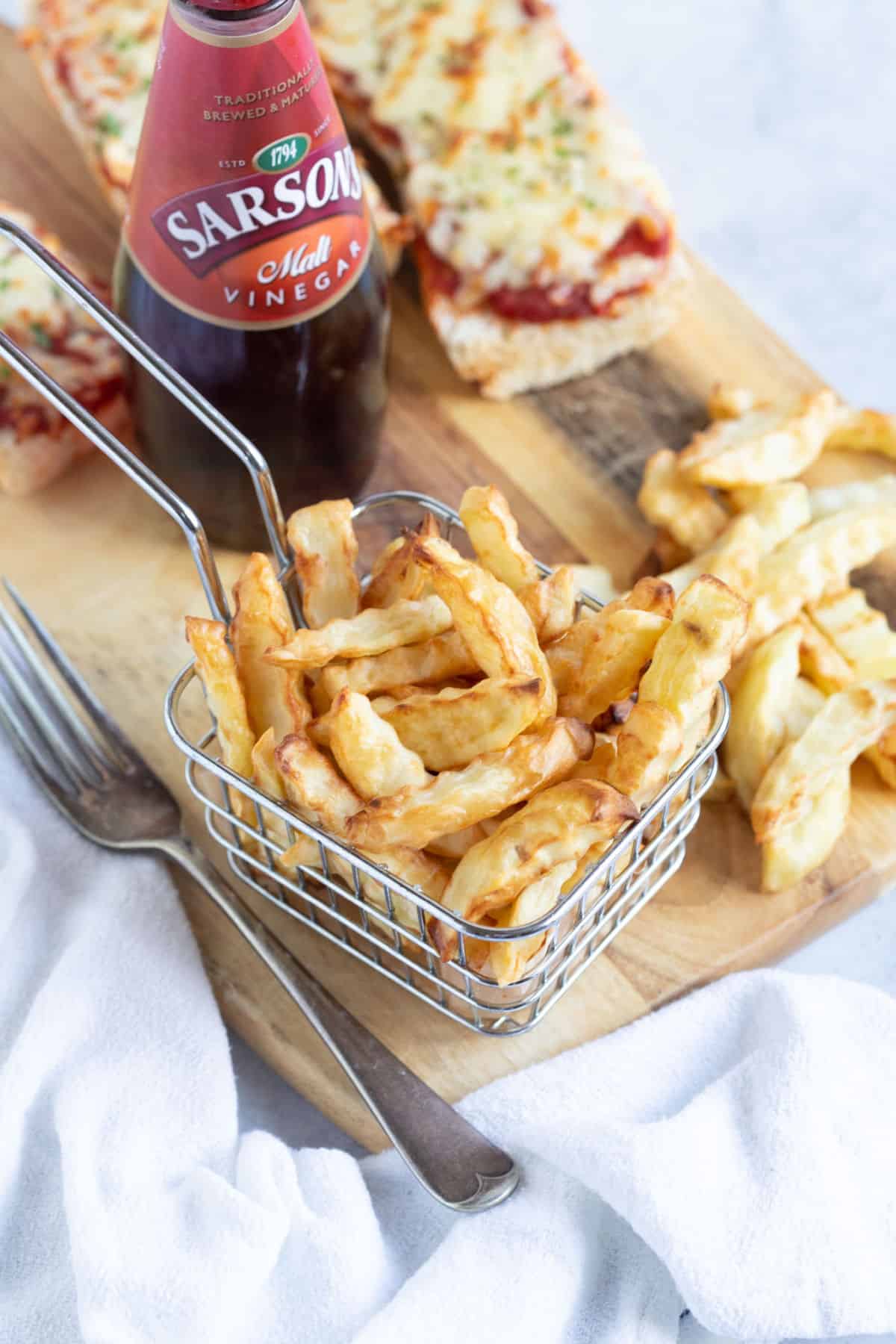 A basket of air fryer chips with baguette pizzas.