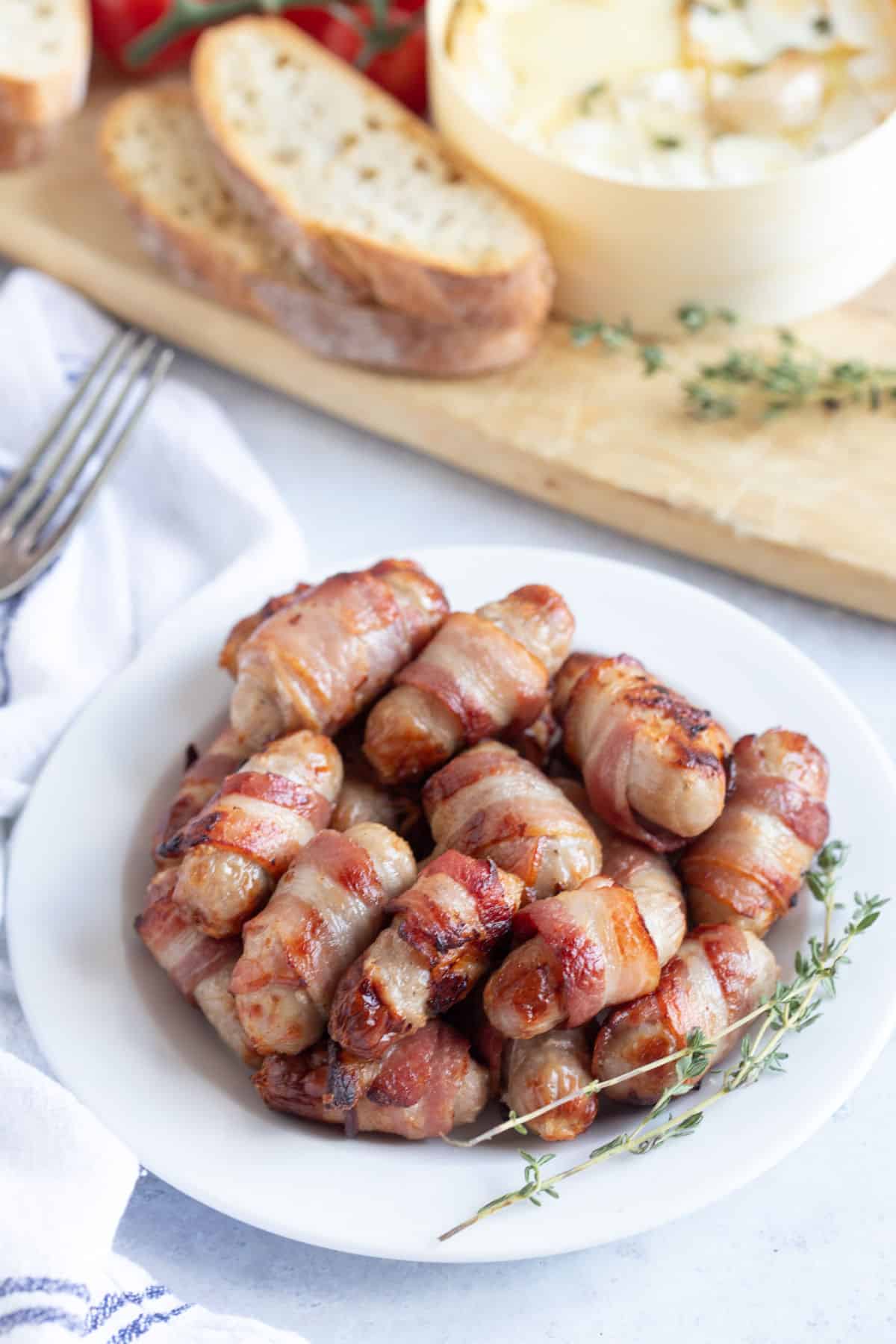 Pigs in blankets on a white plate.