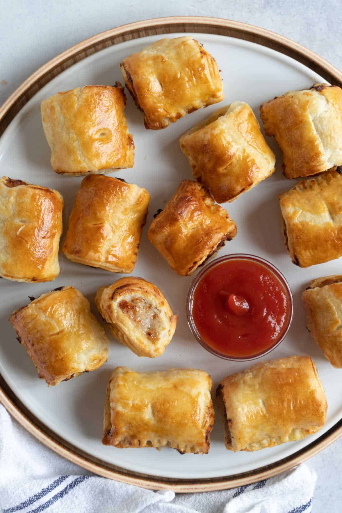 Air fryer sausage rolls on a plate with ketchup.