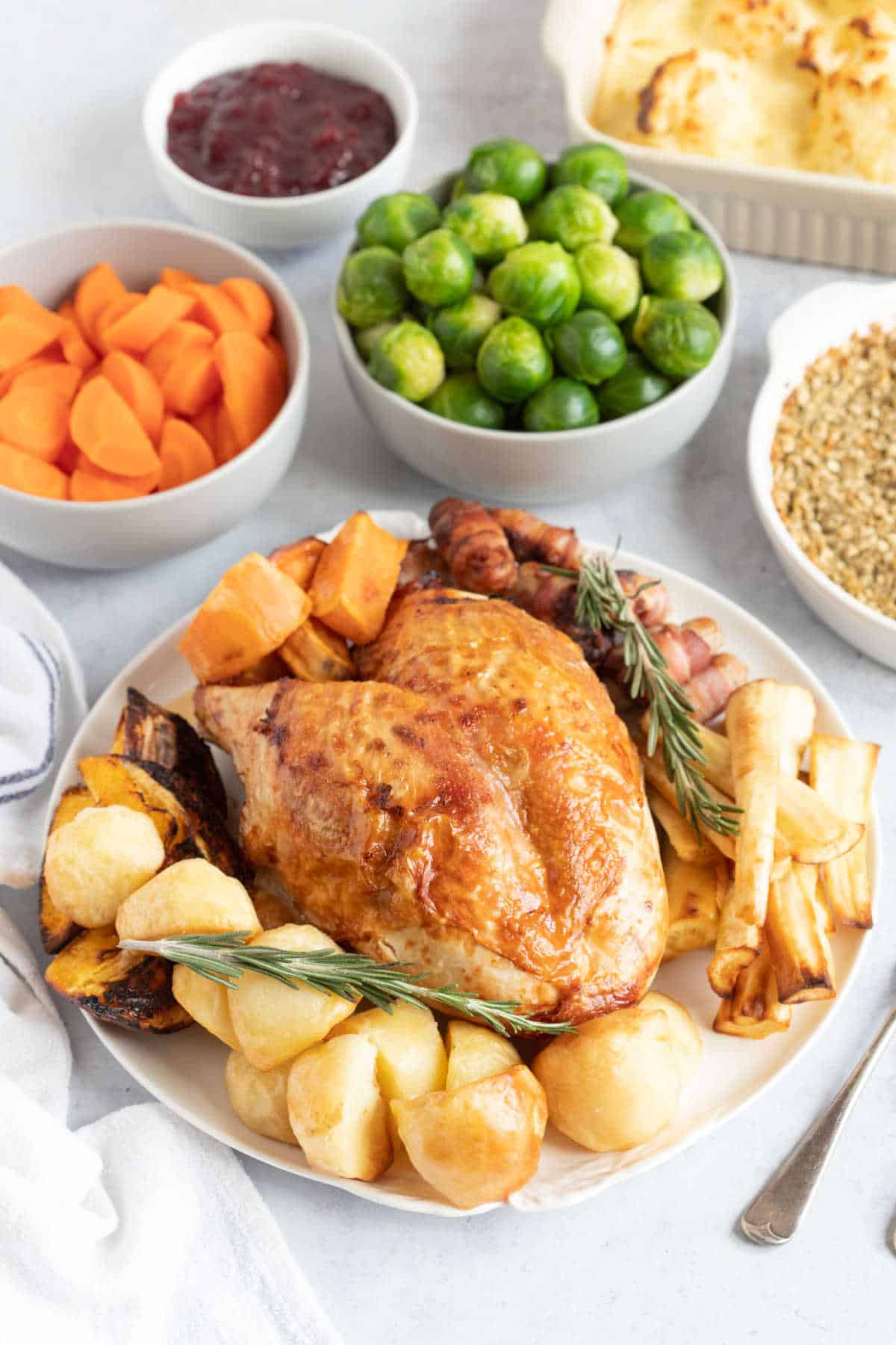 Air fryer turkey crown on a white platter with all the trimmings.