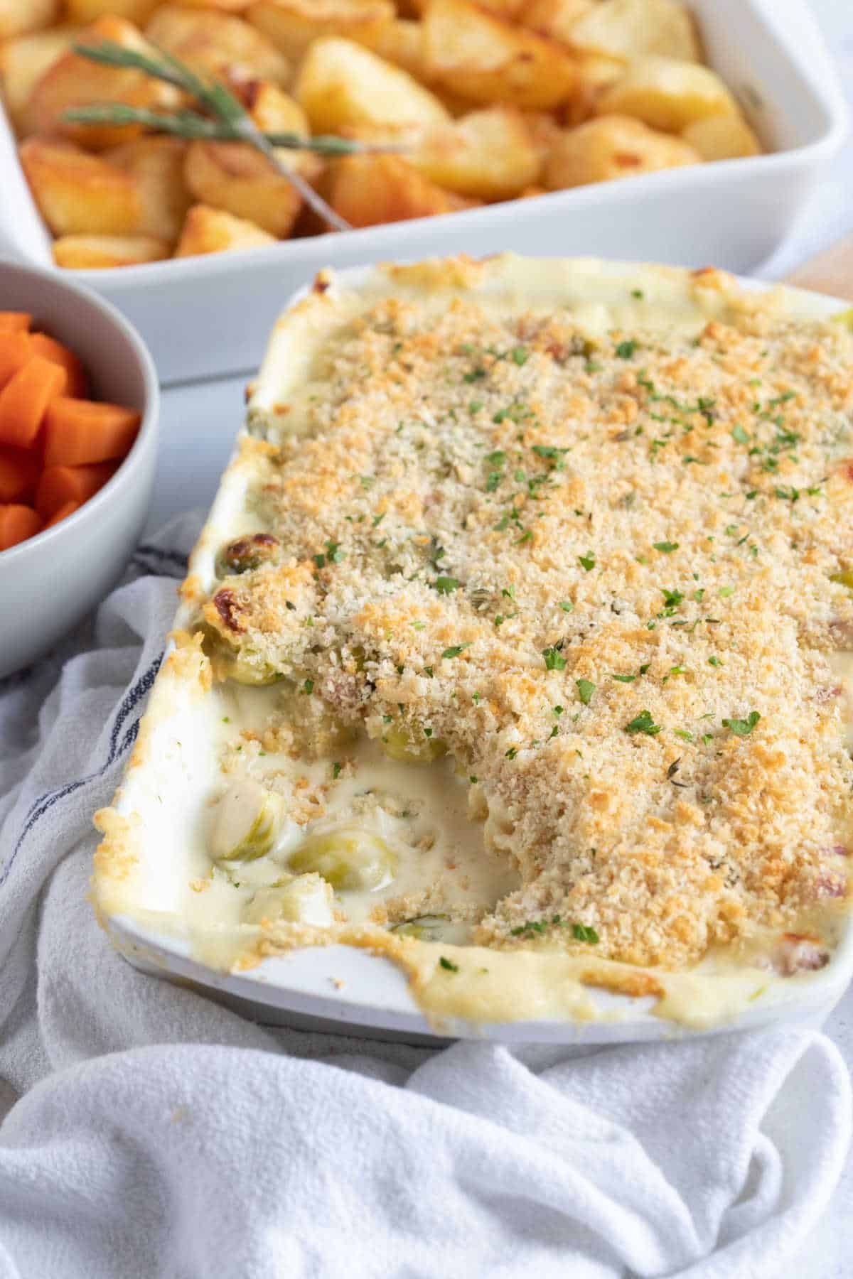 Cheesy Brussels sprouts gratin in a white baking dish.