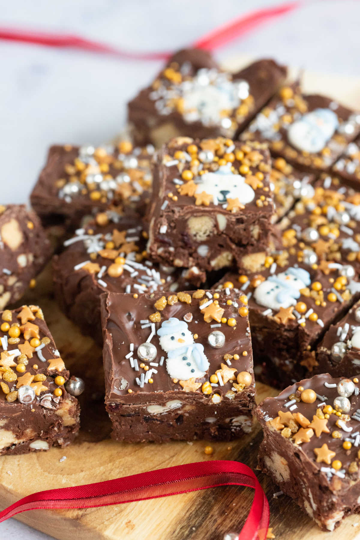 Christmas tiffin squares on a wooden board with red ribbon.