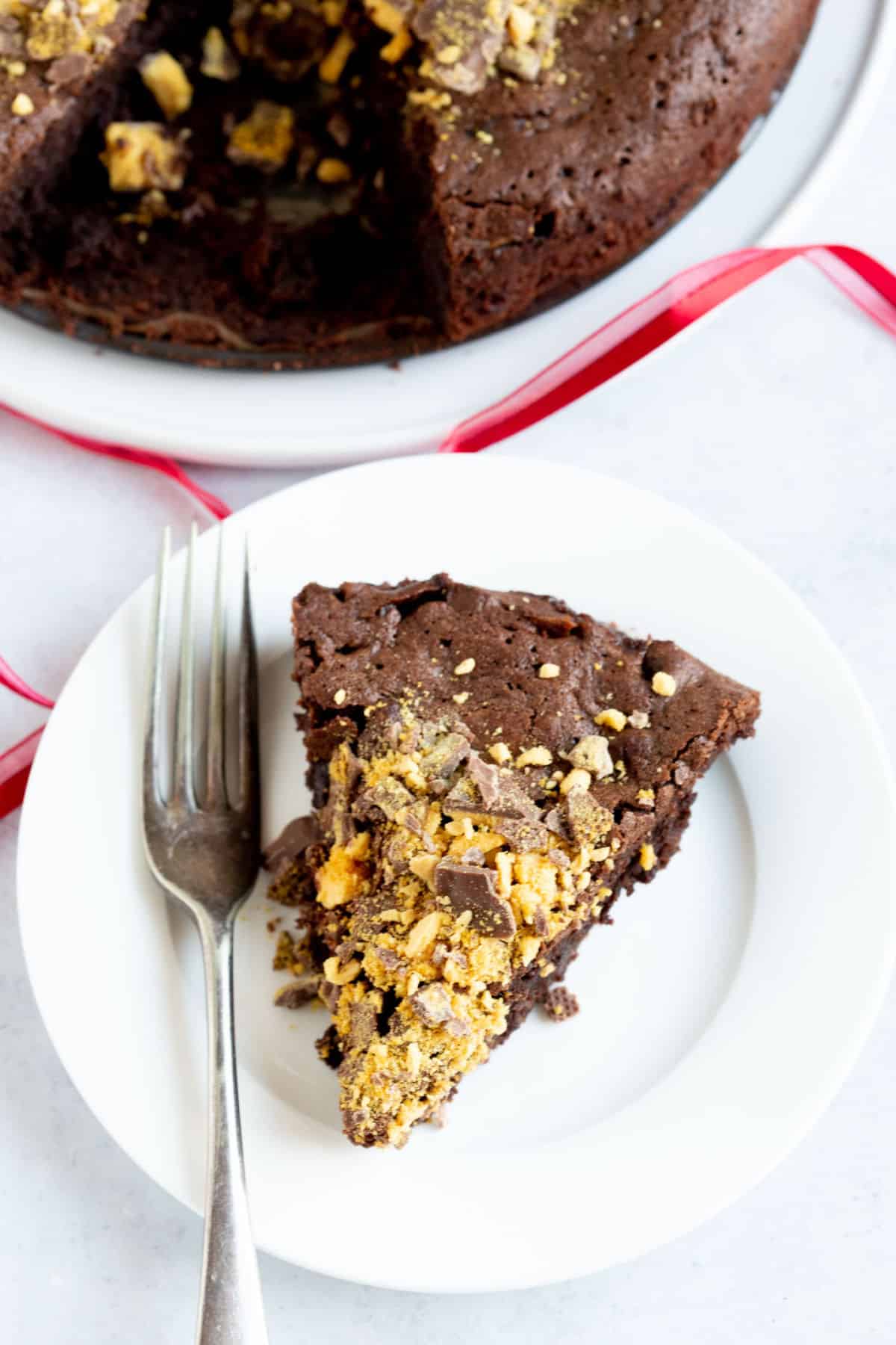A slice of chocolate honeycomb torte on a white plate with a fork at the side.
