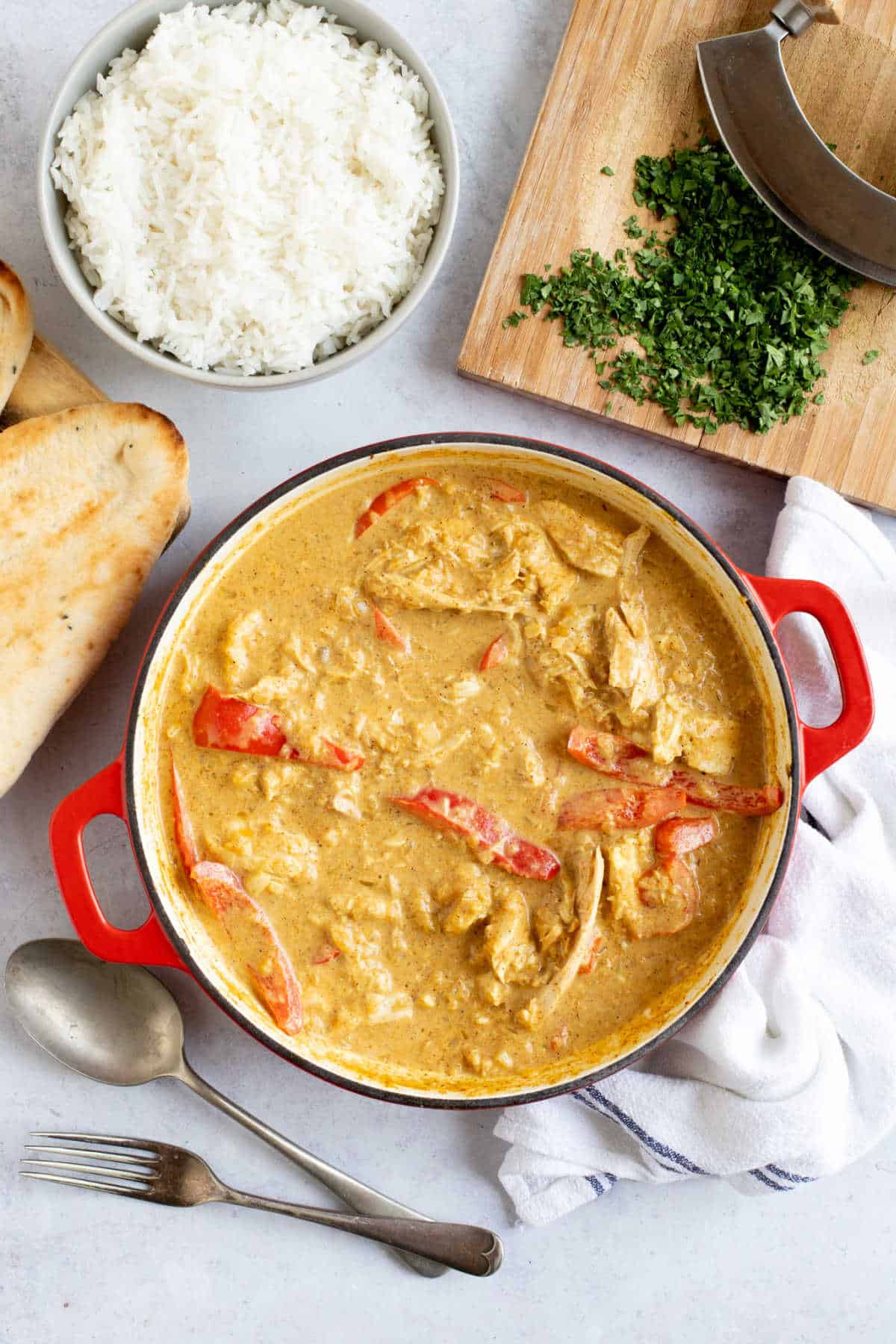 Leftover roast chicken curry with red peppers in a red pan.