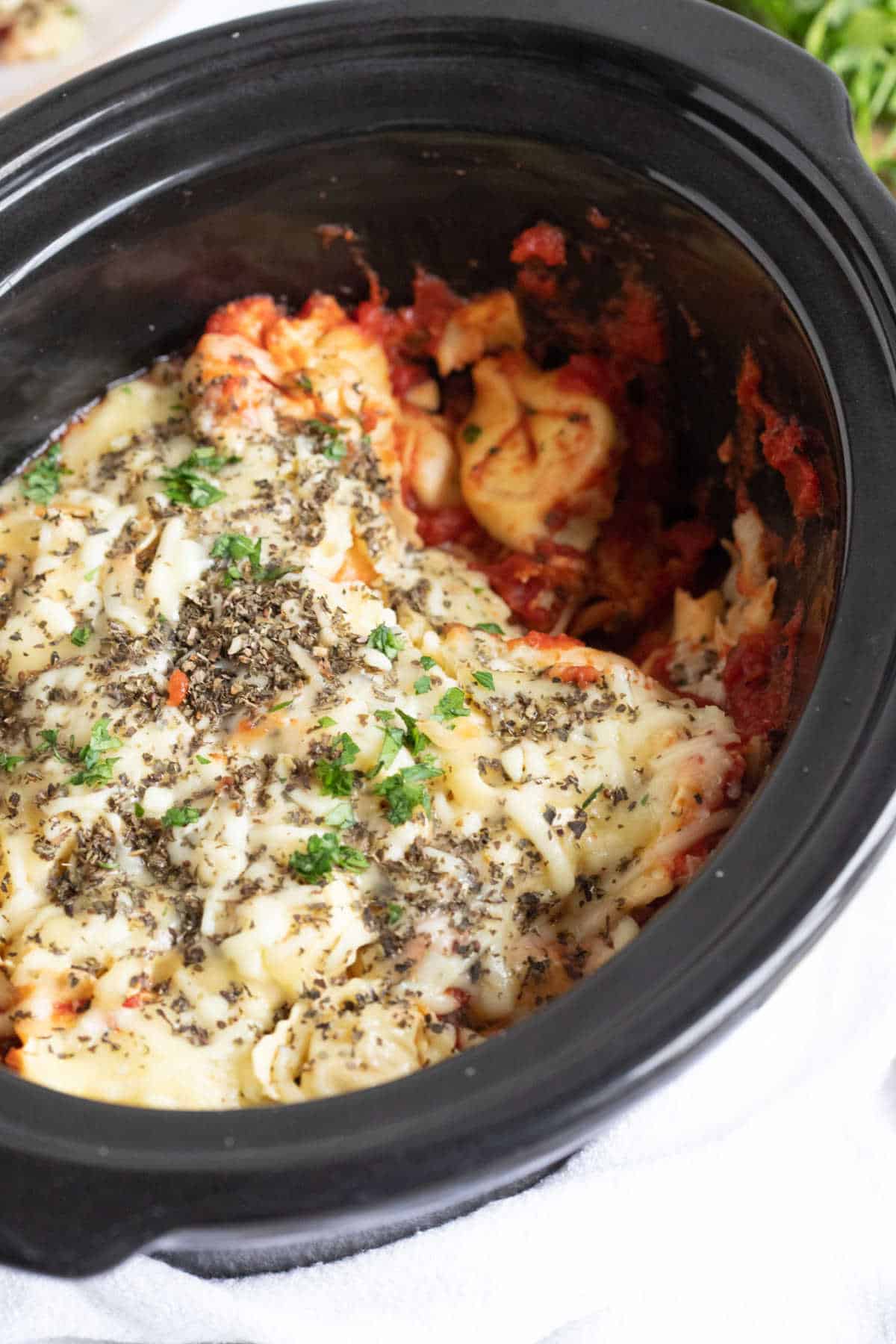 Slow cooker cheesy tortellini in a black crockpot.