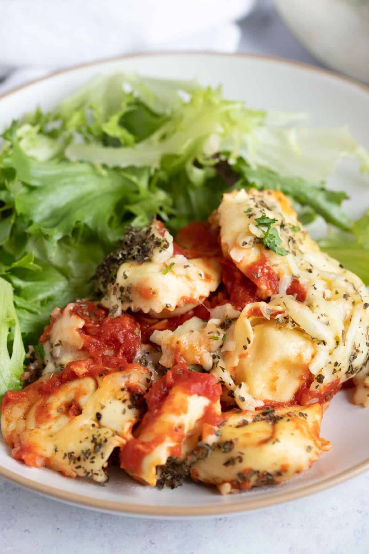 Cheesy slow cooker tortellini on a dinner plate with a green salad.