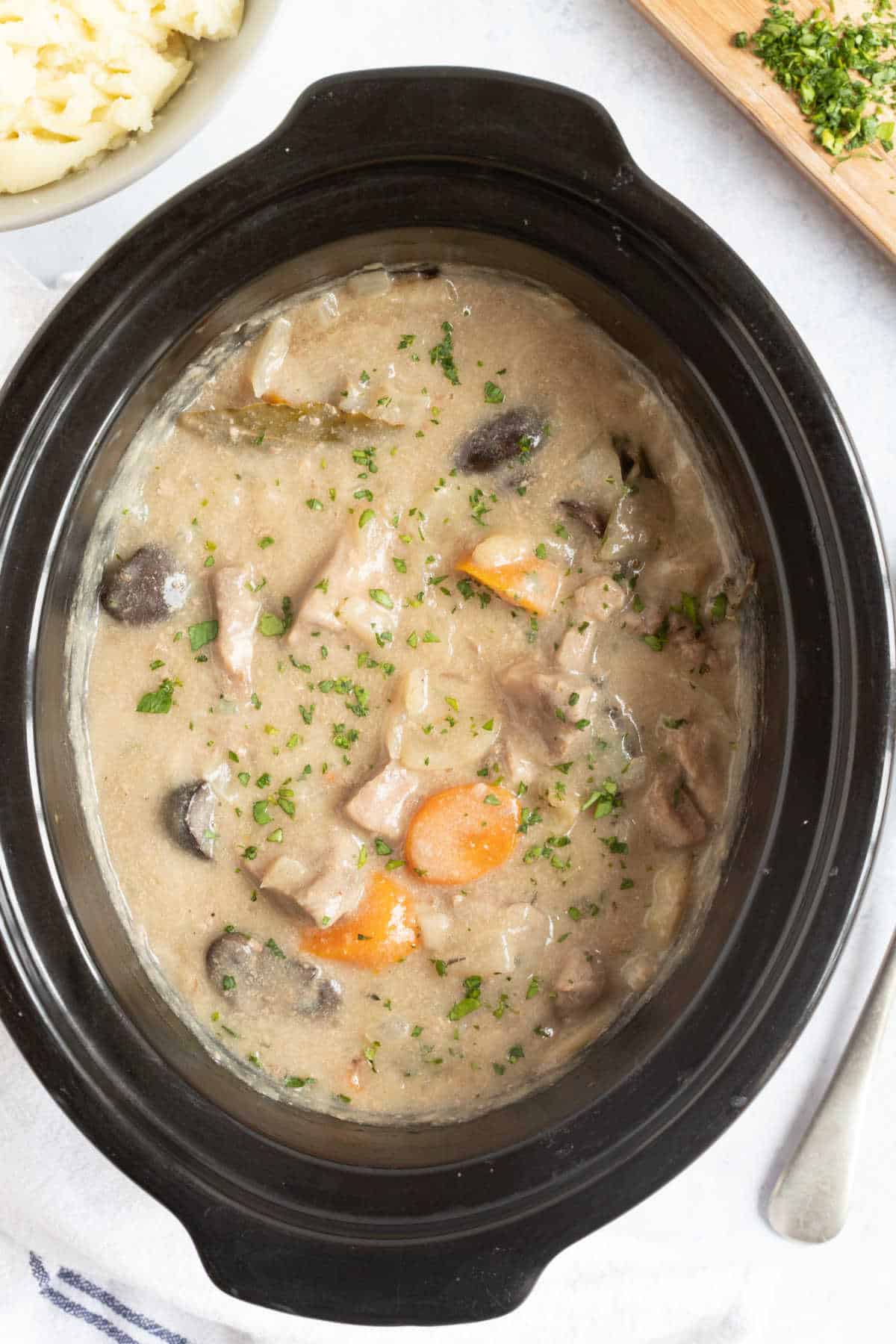 Slow cooker pork and apple casserole in black slow cooker basin.