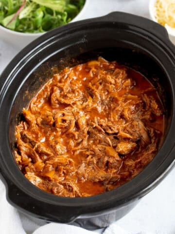 Slow cooker bbq pulled beef in a slow cooker basin.