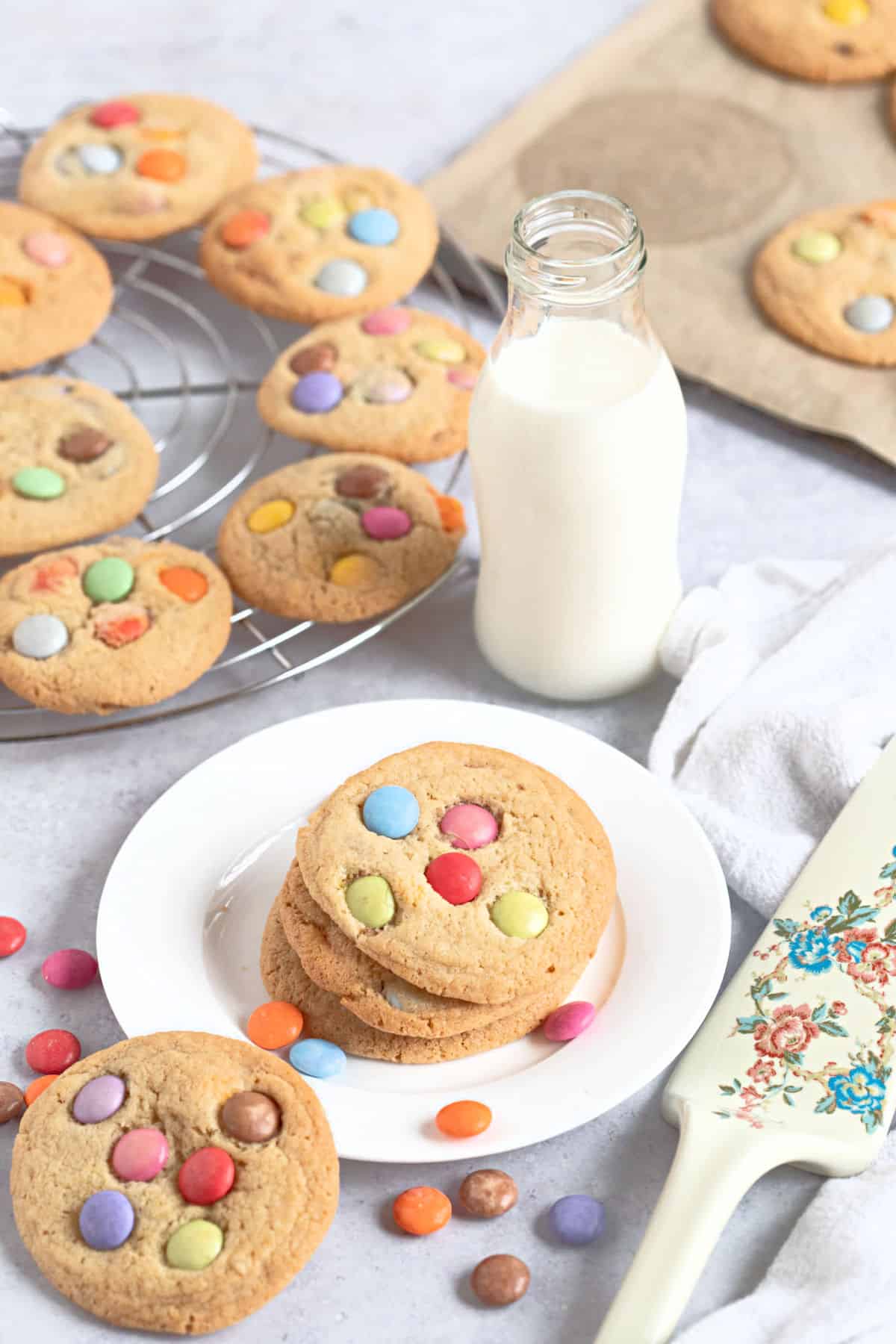 A stack of cookies on a plate with a bottle of milk.