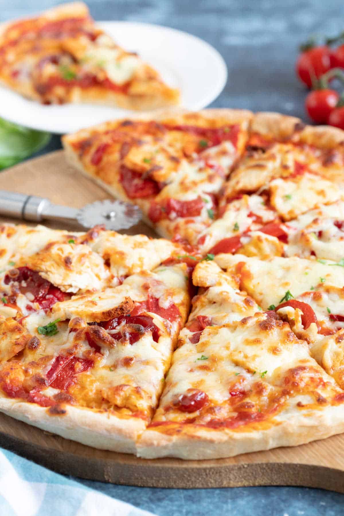 Spicy chicken pizza on a wooden cutting board.