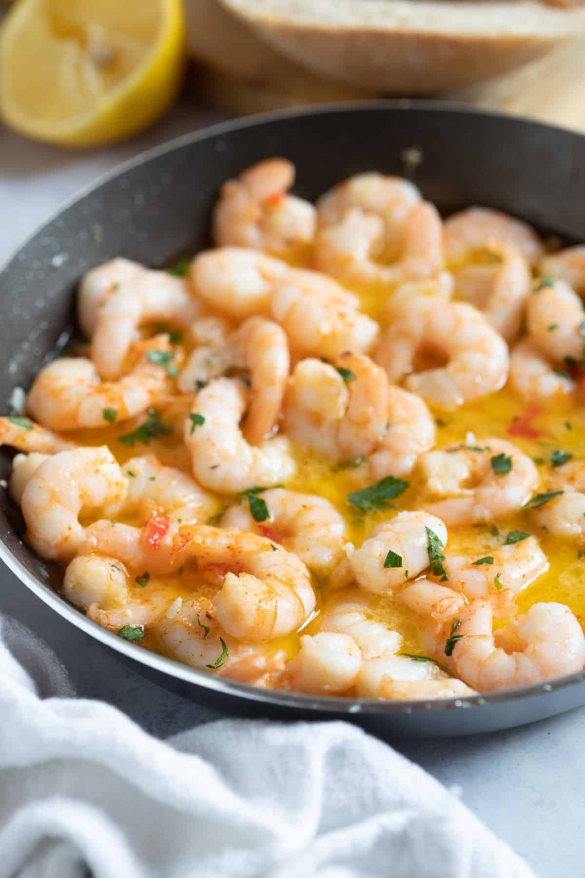 Garlic and chilli prawns (Gambas pil pil) in a black frying pan.