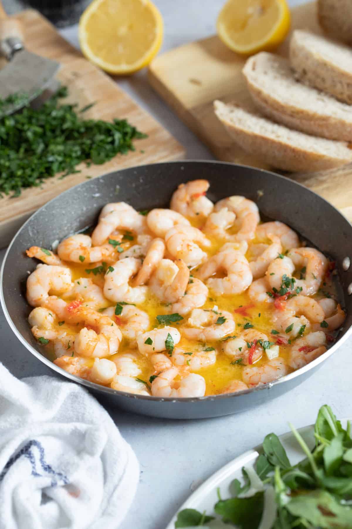 Gambas pil pil in a pan with salad and bread.
