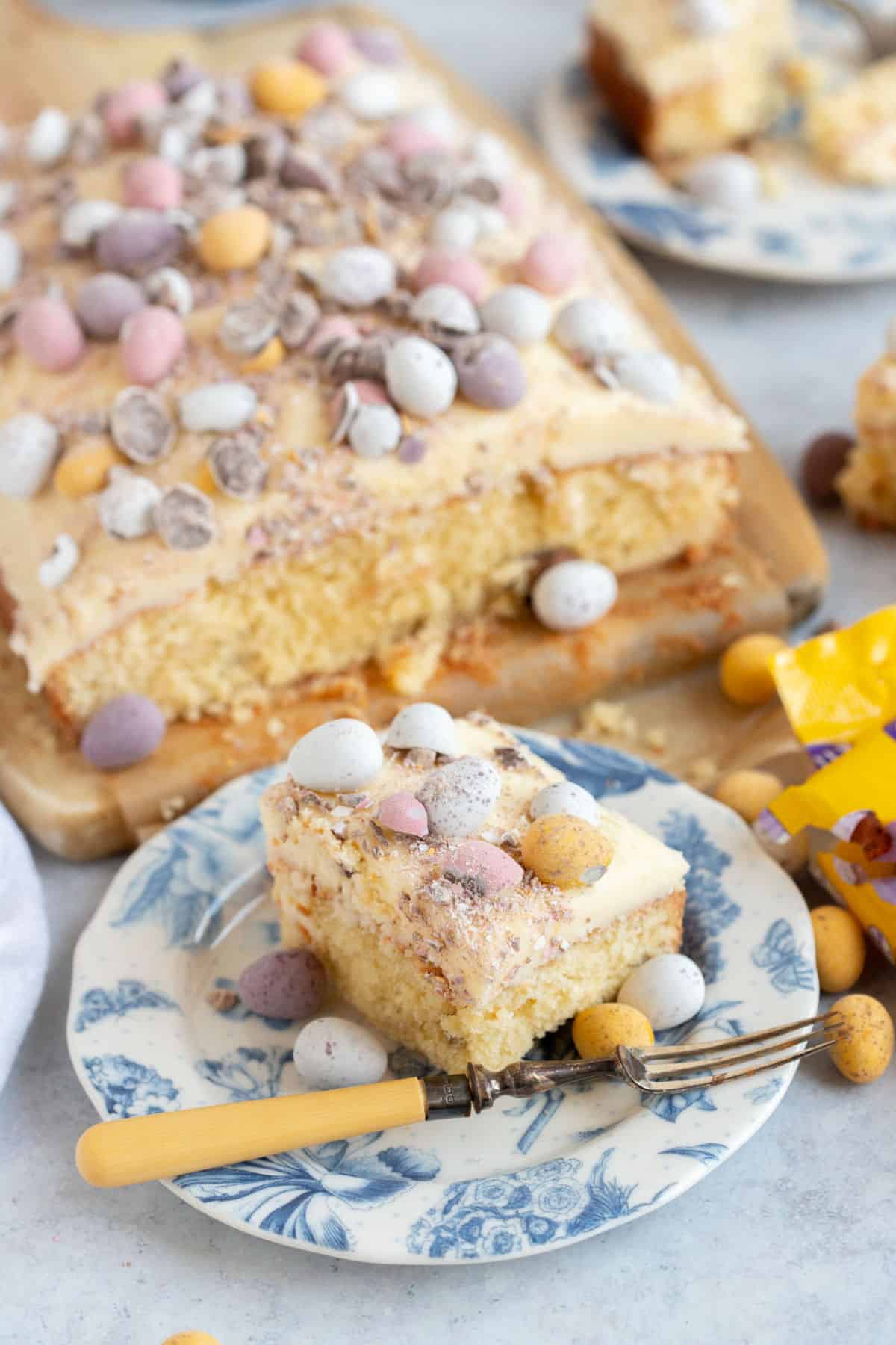 A slice of Easter mini egg traybake cake on a blue and white plate.