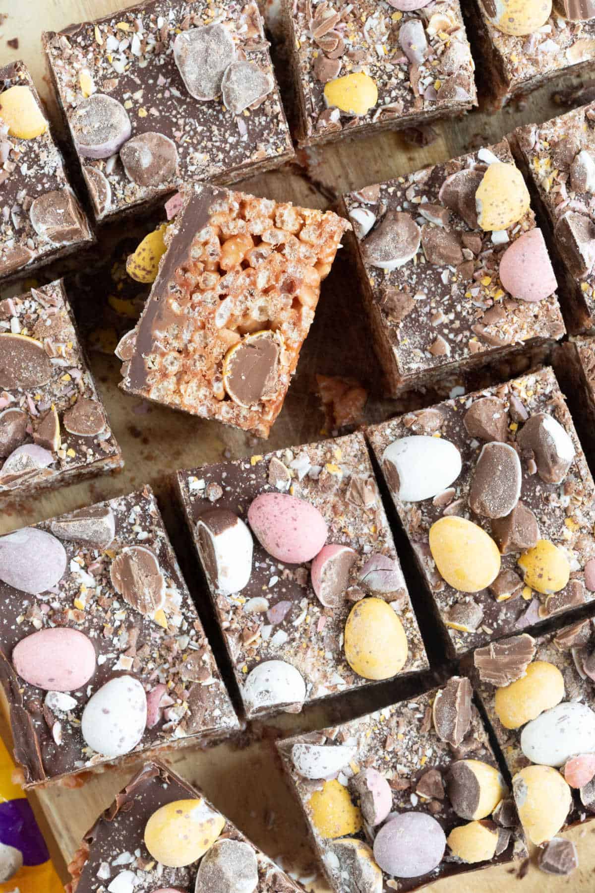 Mini egg rice krispie treats, cut into bars on a wooden board.