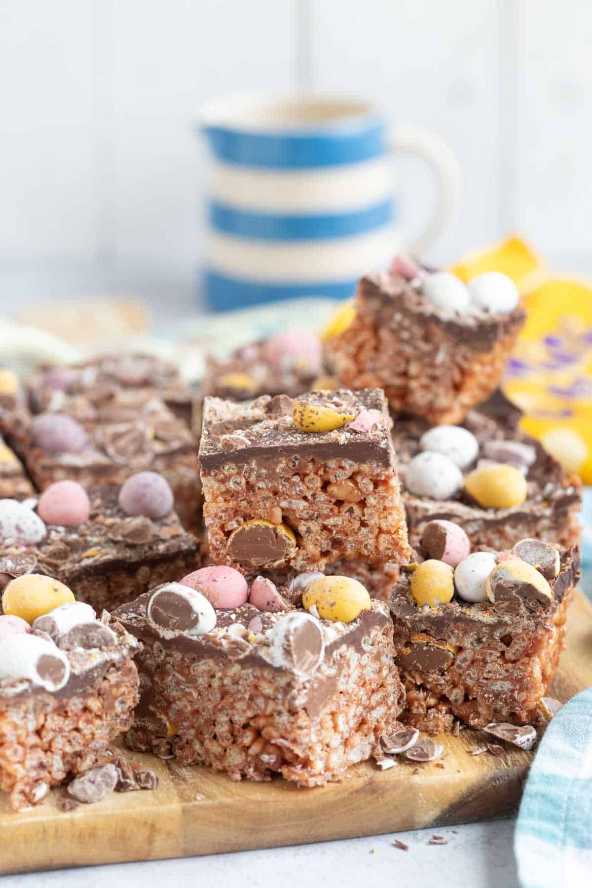 A stack of mini egg rice kirspie squares on a wooden board.