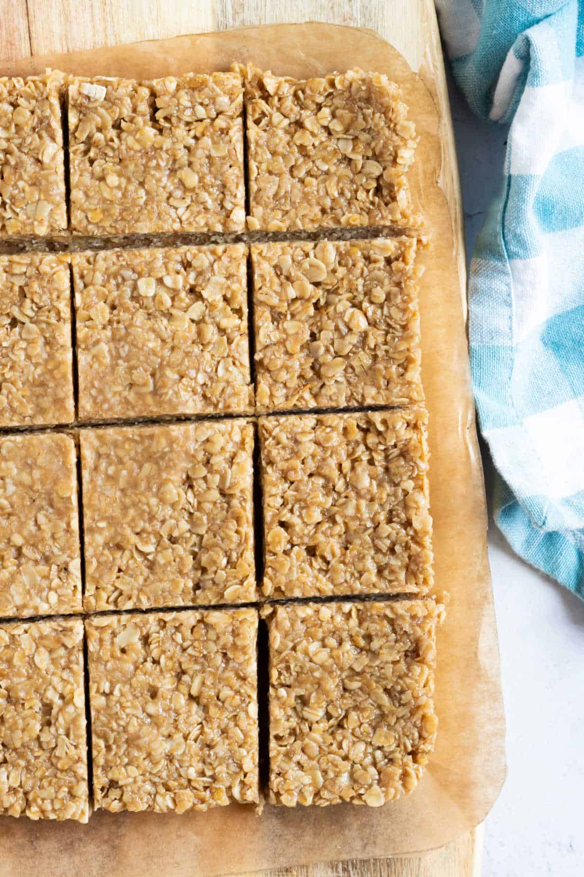 No bake flapjacks cut into squares on a wooden chopping board.