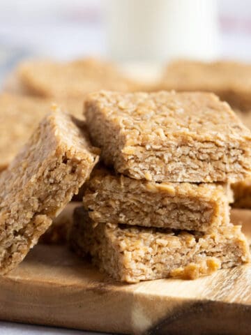 A stack of no bake peanut butter flapjacks on a wooden board.